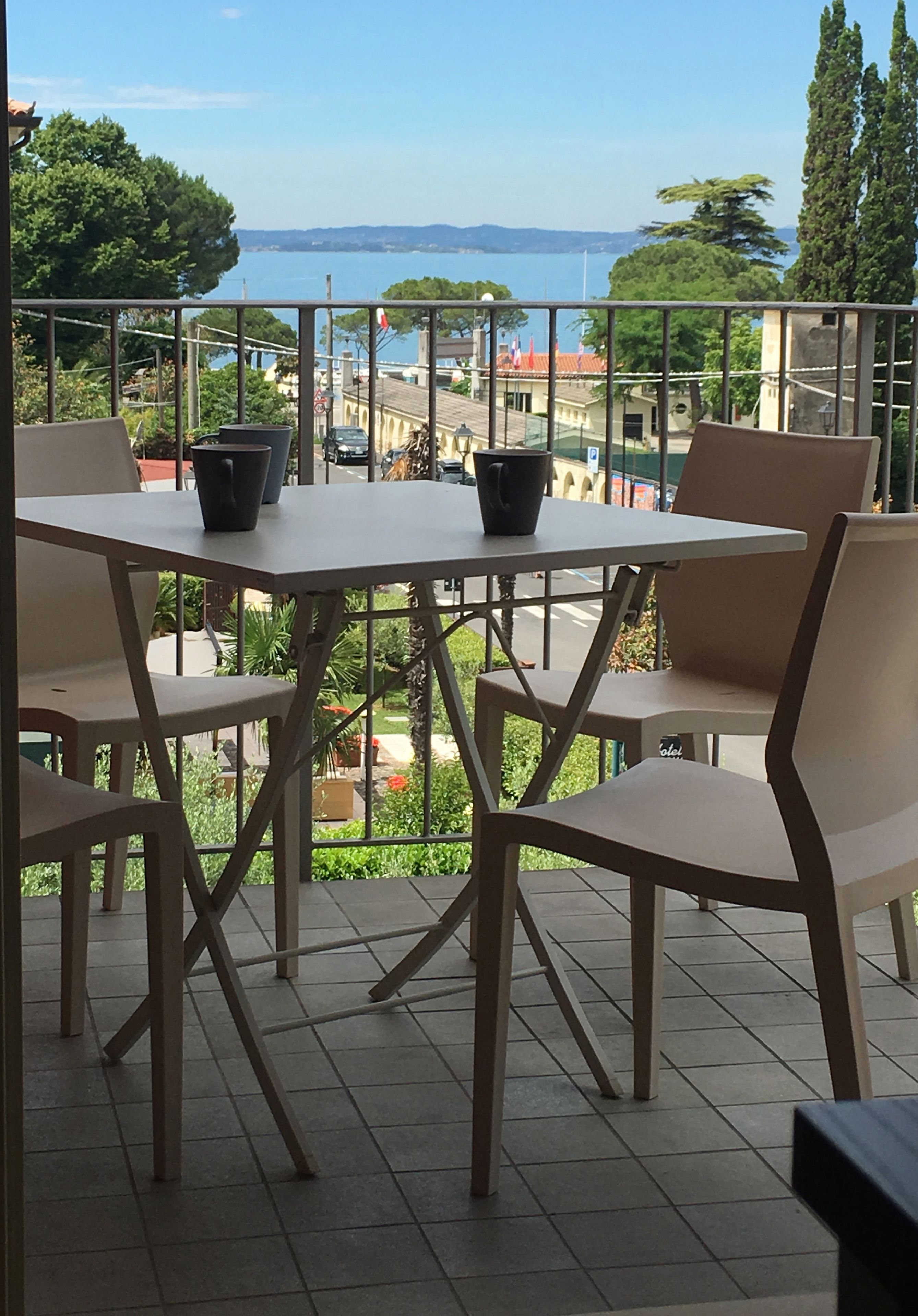 A terrace with a table and chairs, overlooking a scenic view of the sea and buildings.