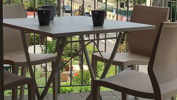 A terrace with a table and chairs, overlooking a scenic view of the sea and buildings.