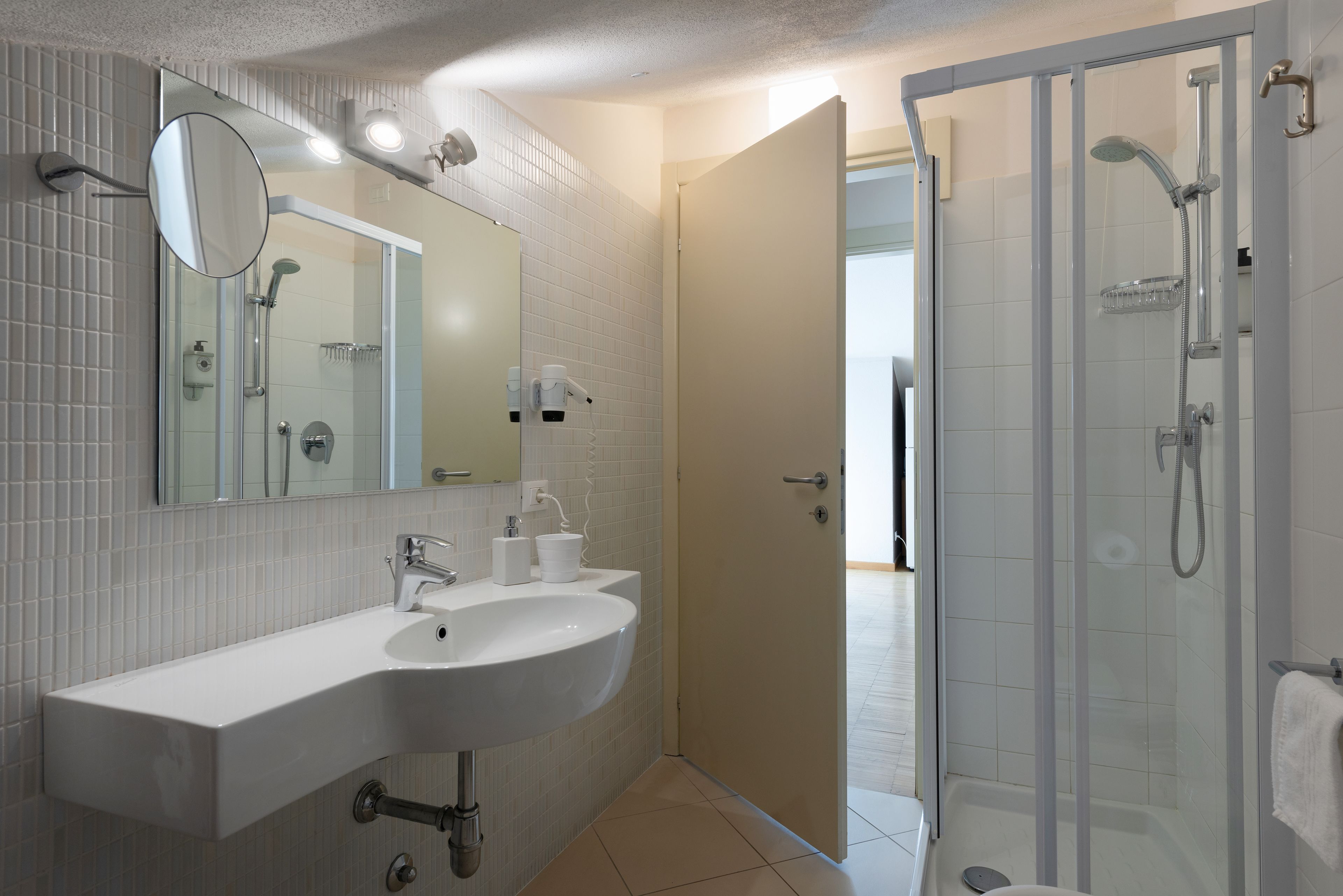 Un baño con lavamanos blanco, espejo y ducha.