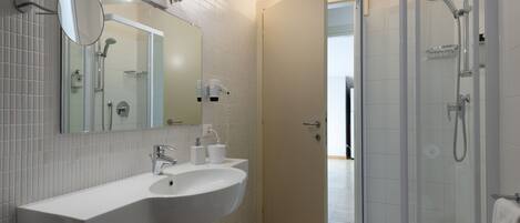 Une salle de bain avec un lavabo blanc, un miroir et une douche.