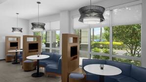 Un área de estar interior moderna con sofás azules, mesas redondas y televisores integrados.