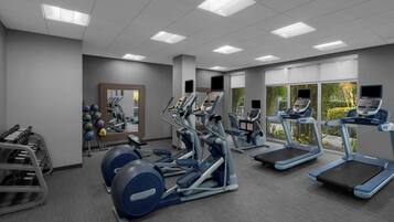 A modern gym with treadmills, elliptical machines, and weight equipment.
