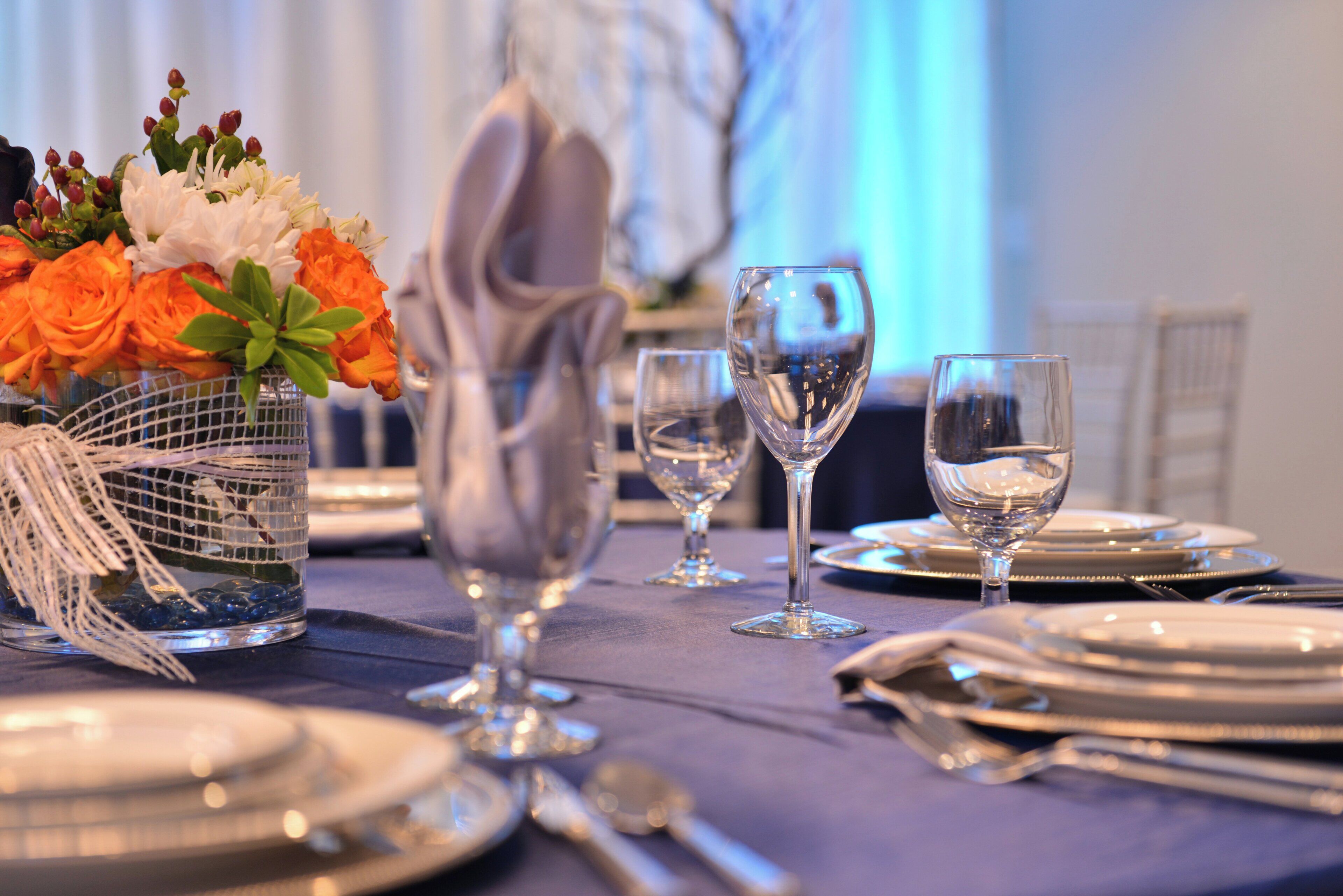 A table set for a formal dinner with clear glassware, a vase of flowers, and a decorative centerpiece.