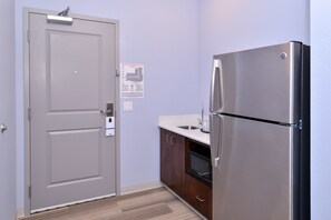 Una cocina funcional con un refrigerador de acero inoxidable, un microondas y un lavamanos.