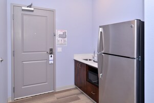 Una cocina funcional con un refrigerador de acero inoxidable, un microondas y un lavamanos.