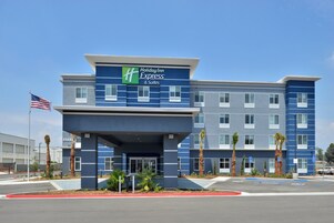 Edificio de Holiday Inn Express & Suites con diseño moderno, que cuenta con una entrada destacada y un asta con la bandera estadounidense.