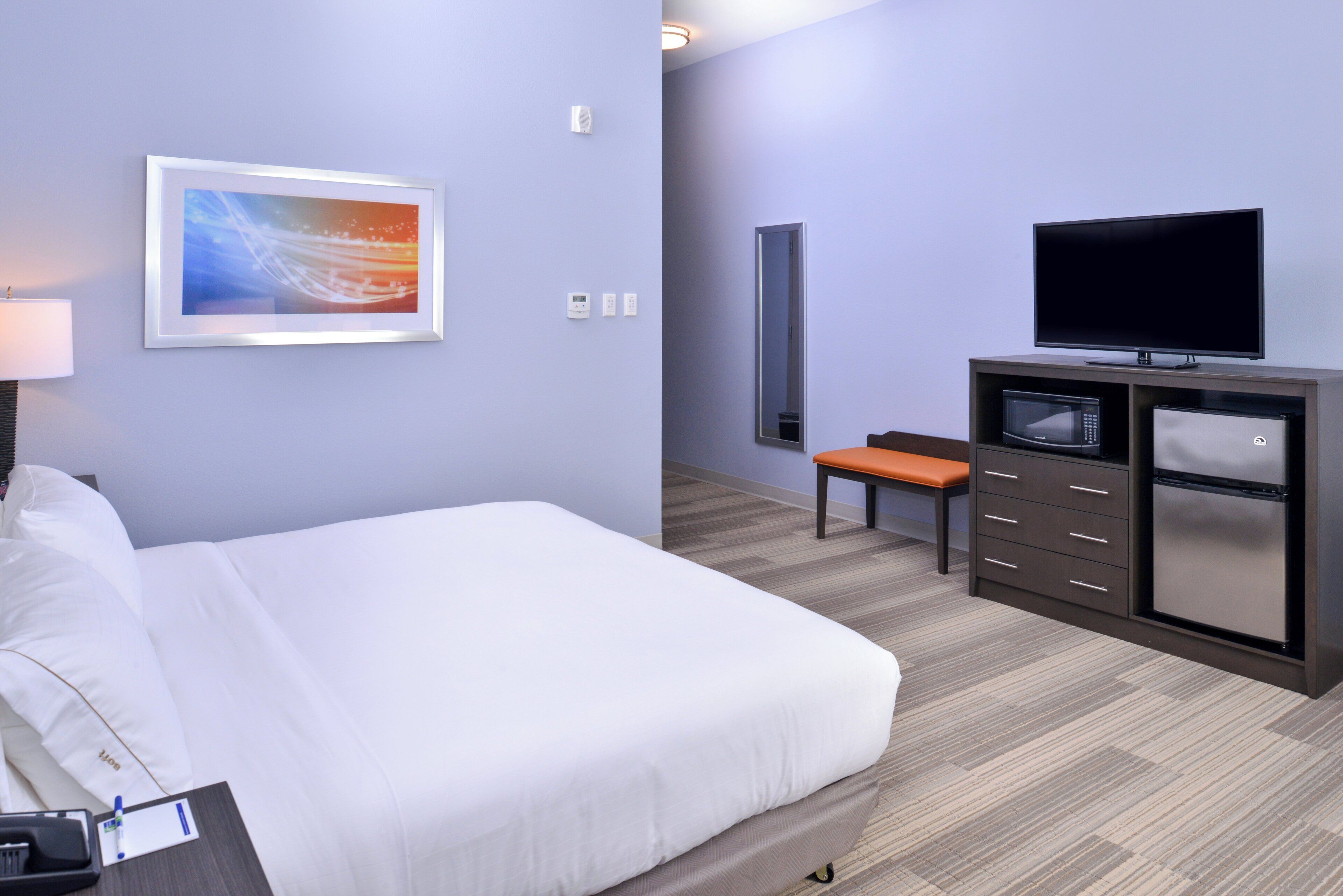 Ein Hotelzimmer mit Bett, Fernseher, Mikrowelle und einer Sitzecke.