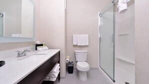 Een moderne badkamer met een douchecabine van glas, een wit wastafelmeubel met spiegel en een toilet.