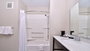 Een moderne badkamer met een bad, douche en wastafel.