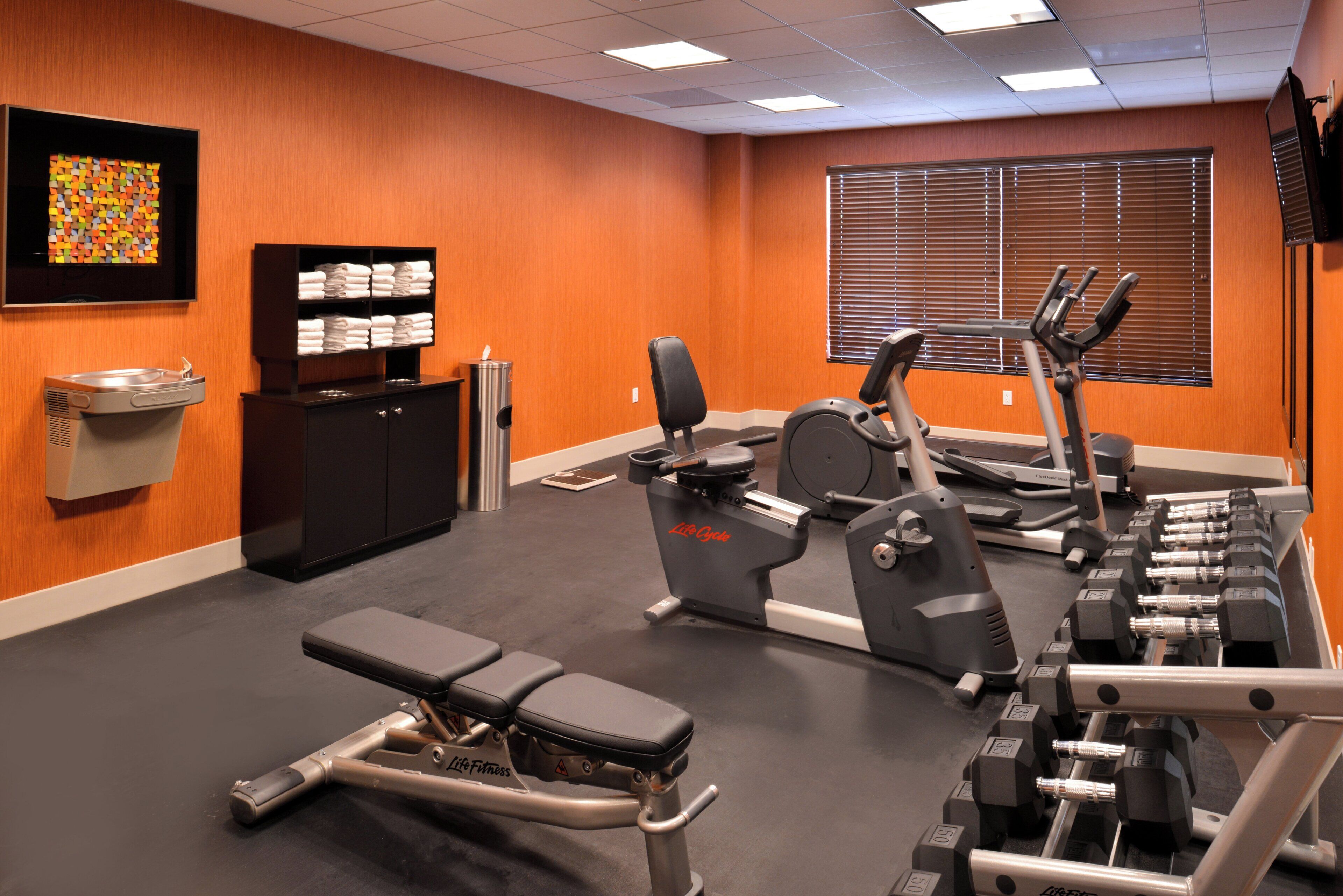 A gym with exercise equipment, a weight bench, and a wall-mounted towel rack.