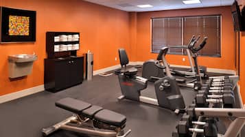 A gym with exercise equipment, a weight bench, and a wall-mounted towel rack.
