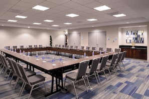 Una sala de conferencias con una larga mesa, sillas, botellas de agua y una estación de café.