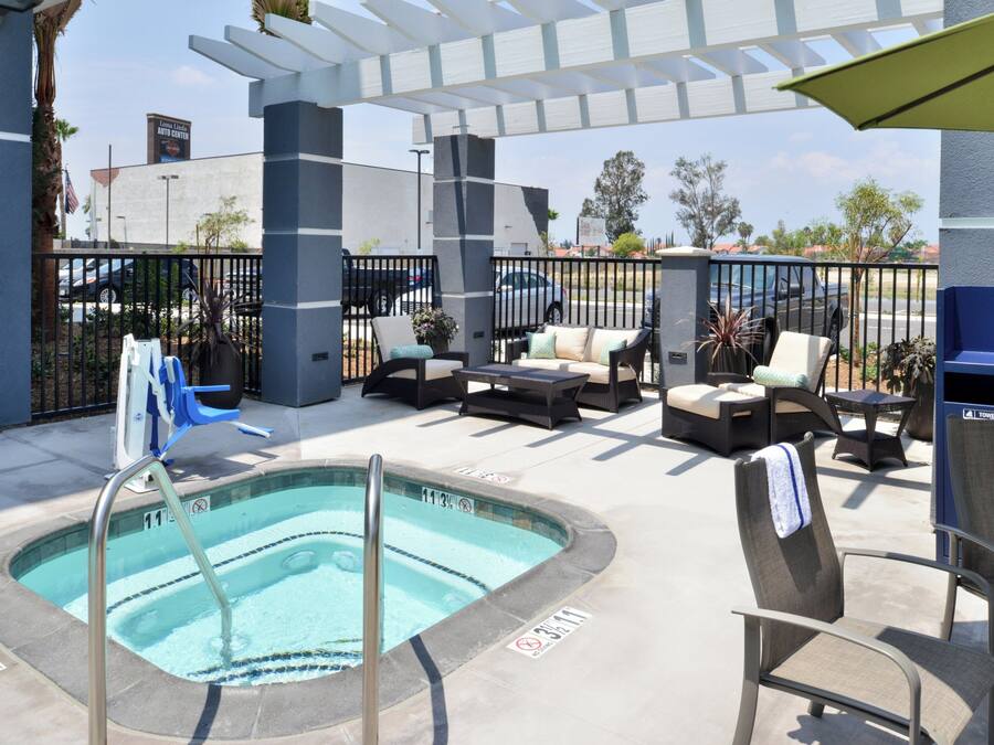 An outdoor pool area with lounge chairs and a hot tub.