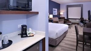 Een hotelkamer met kitchenette, een bed, een bureau en een televisie.