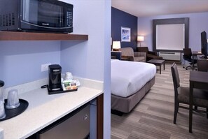 Una habitación de hotel con kitchenette, una cama, un escritorio y un televisor.