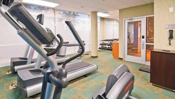 Un gimnasio con cintas de correr, elípticas y pesas.