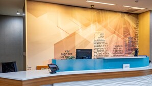 A reception desk with a modern design, featuring a wooden finish and a white counter. - SpringHill Suites by Marriott Baton Rouge Gonzales (Gonzales)