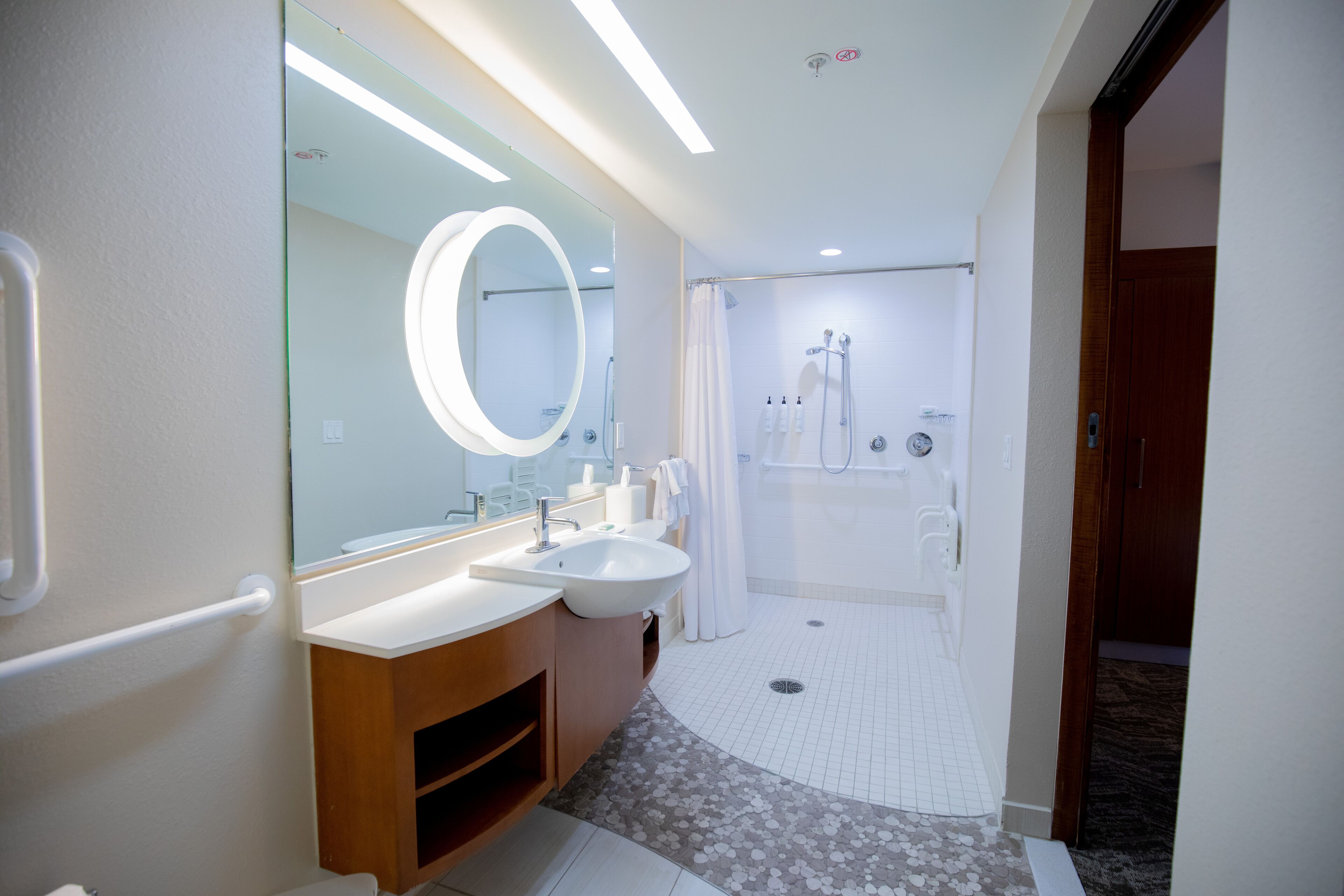 Un baño moderno con un espejo grande, dos lavamanos, una ducha y un inodoro.