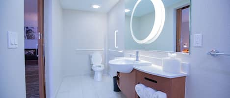 Un baño moderno con lavamanos, espejo y retrete blancos.