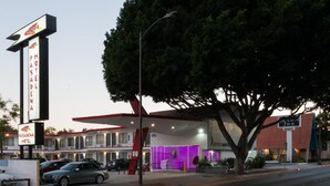 A motel with a prominent sign, a covered parking area, and a building with a purple-lit interior. - Astro Pasadena Hotel (Pasadena)