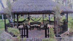 A thatched-roof gazebo with outdoor seating and potted plants. - Hotel D'Anatureza (Maceió)