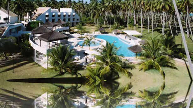 A resort with a central pool surrounded by palm trees and a building with multiple balconies. - Hotel D'Anatureza (Maceió)
