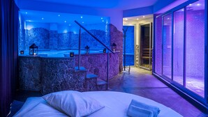 Un spa moderno con pared de piedra, un jacuzzi y un ventanal grande.
