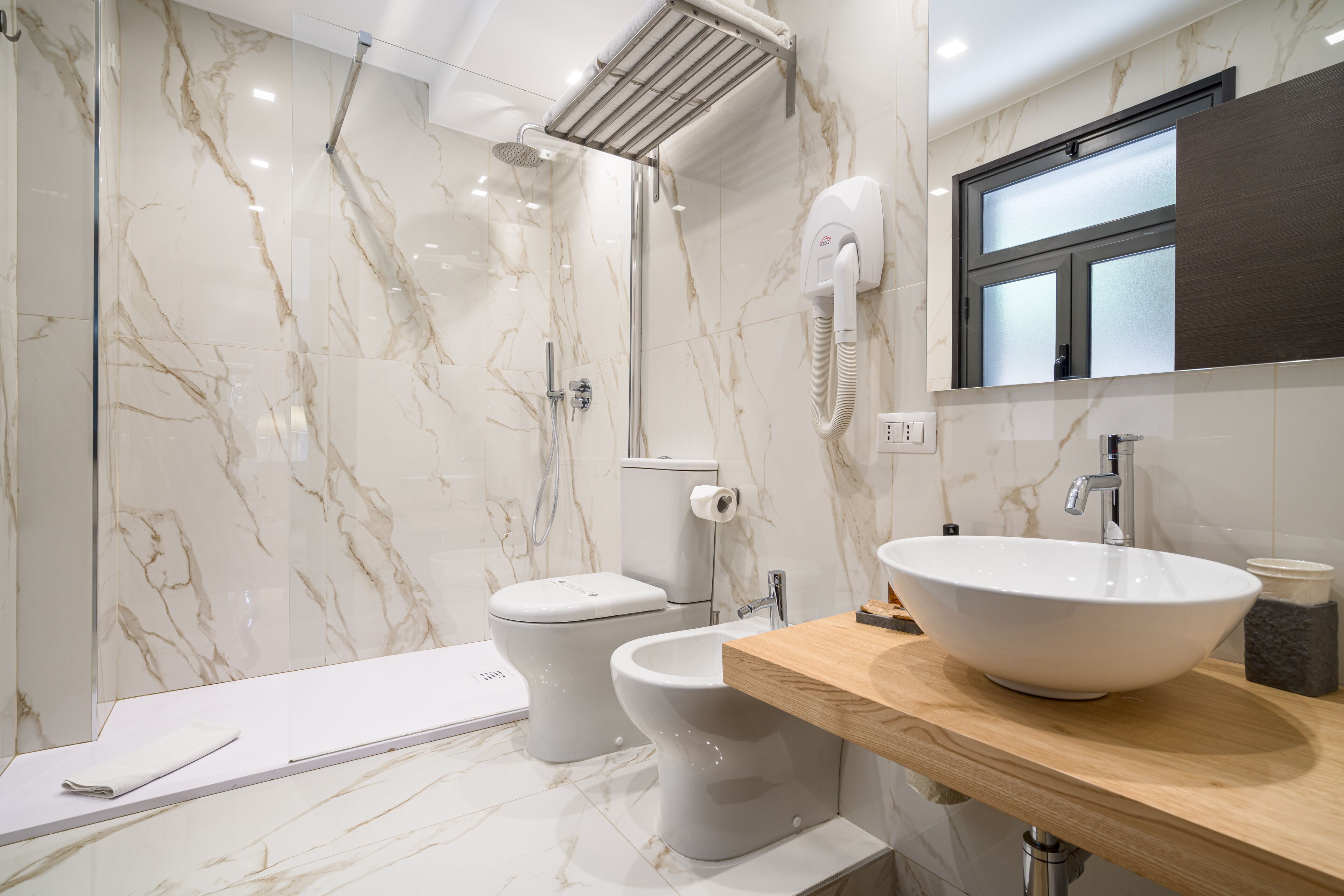 Un bagno moderno con una parete in marmo, un lavabo bianco e una cabina doccia.