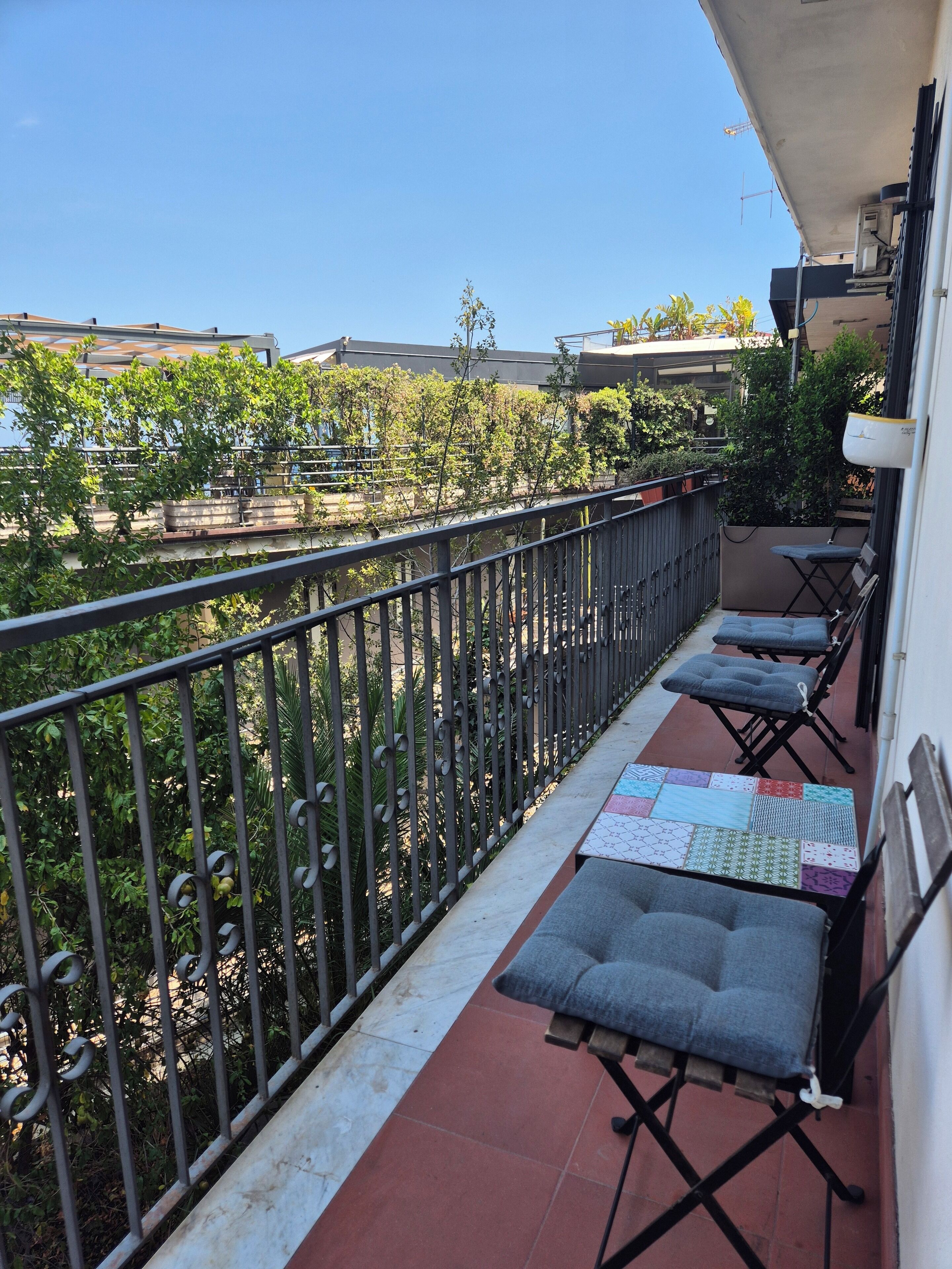 A balcony with a metal railing, two folding chairs with cushions, and a tiled floor.
