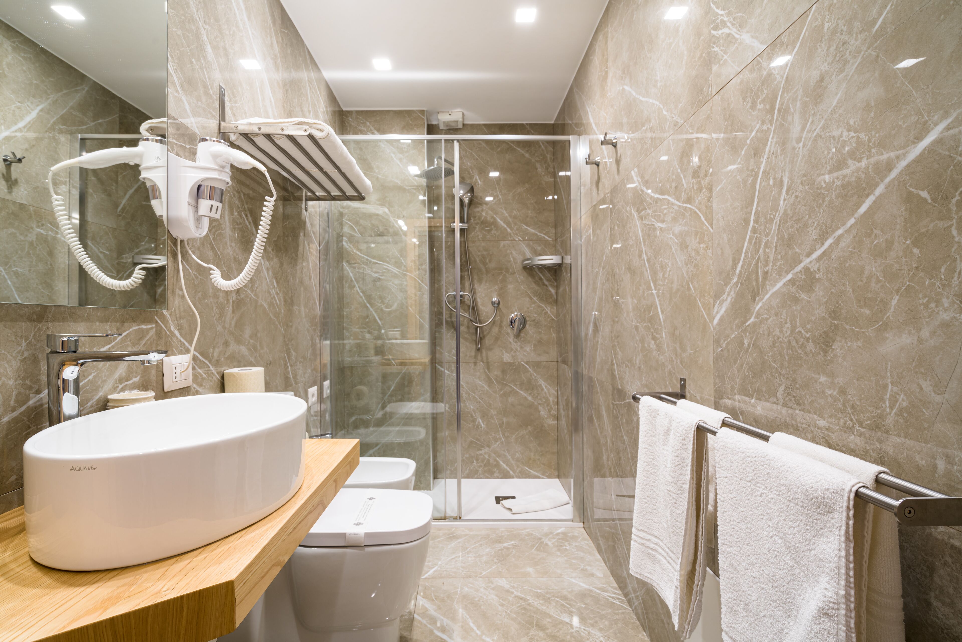 Un bagno moderno con un lavabo in marmo, una cabina doccia in vetro e un porta asciugamani.