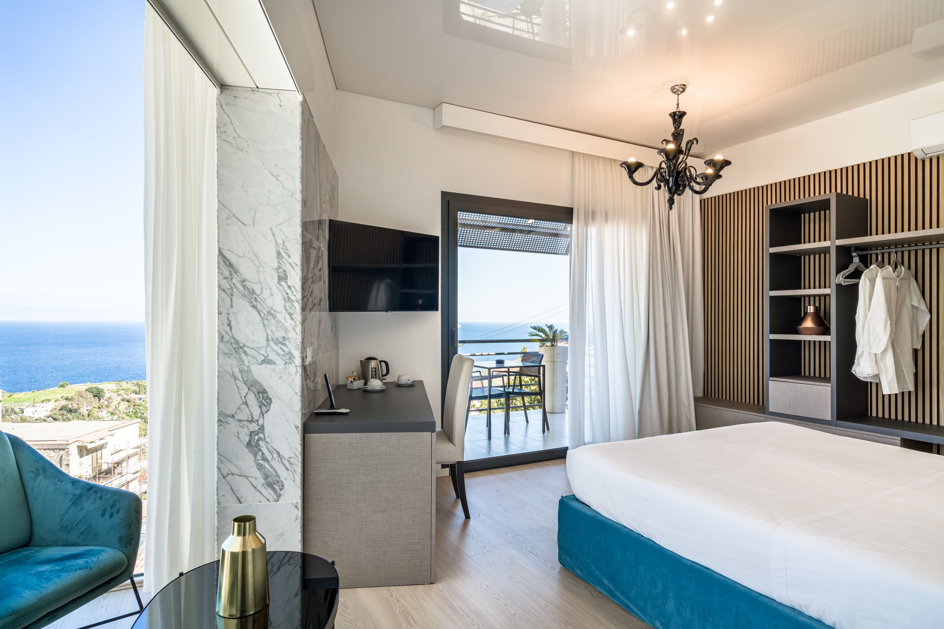 Une chambre d’hôtel moderne avec un grand lit, un bureau et une vue sur la mer.