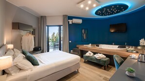 Una habitación de hotel moderna con cama, escritorio, baño con lavamanos y televisión.