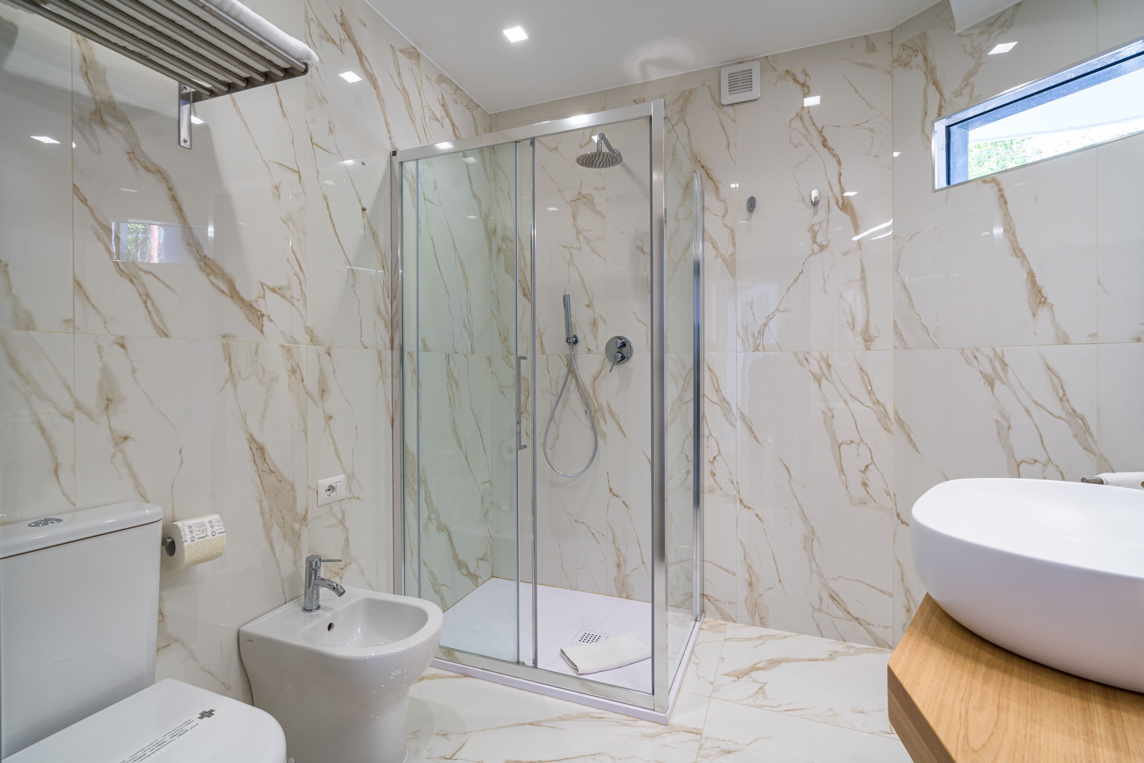 Un baño con ducha envuelta en vidrio, un lavabo y un bidé.