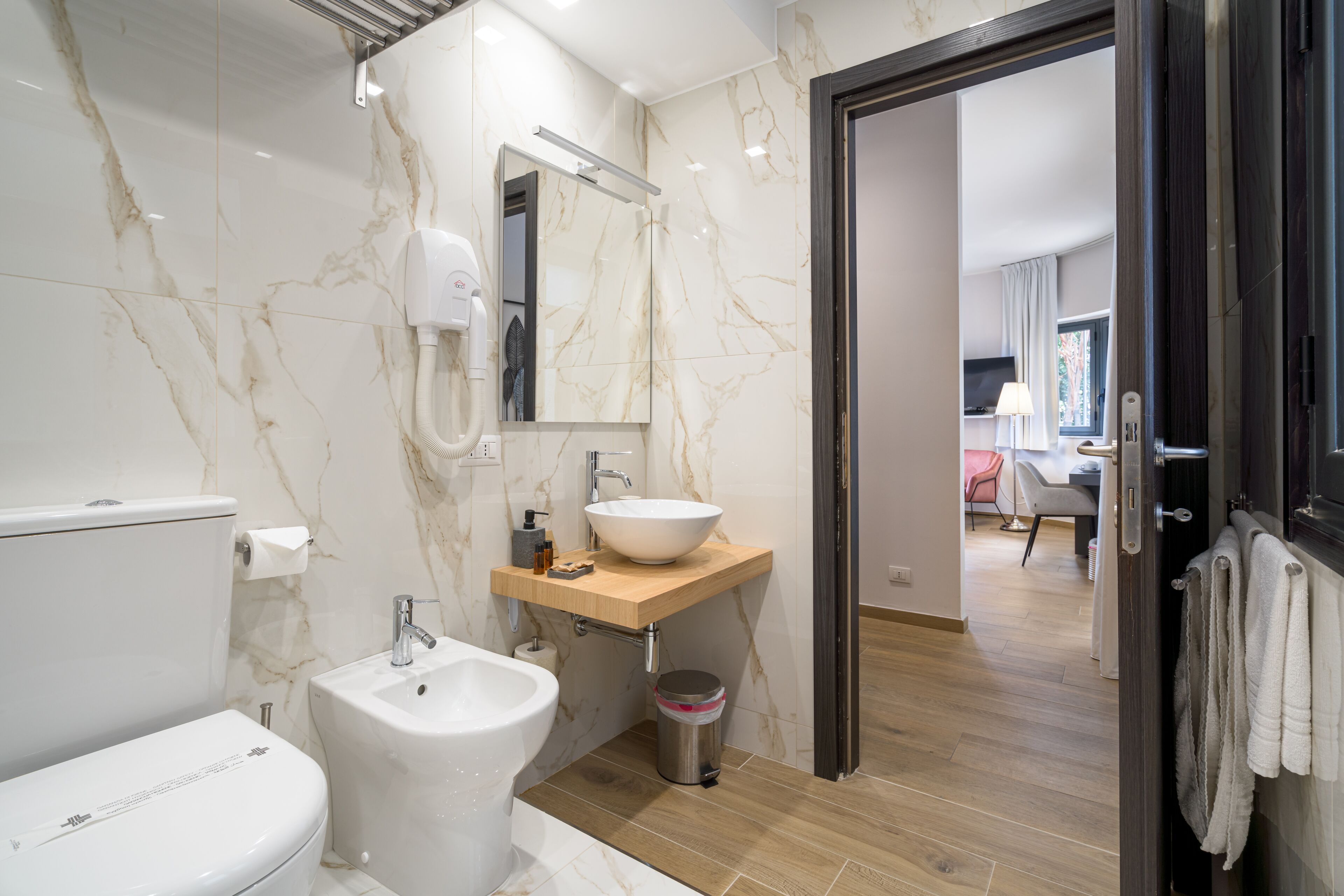 Une salle de bain moderne équipée de toilettes, d’un bidet, d’un lavabo et d’un miroir.