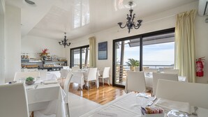 Un restaurante con mesas y sillas blancas, un candelabro y vistas al mar.