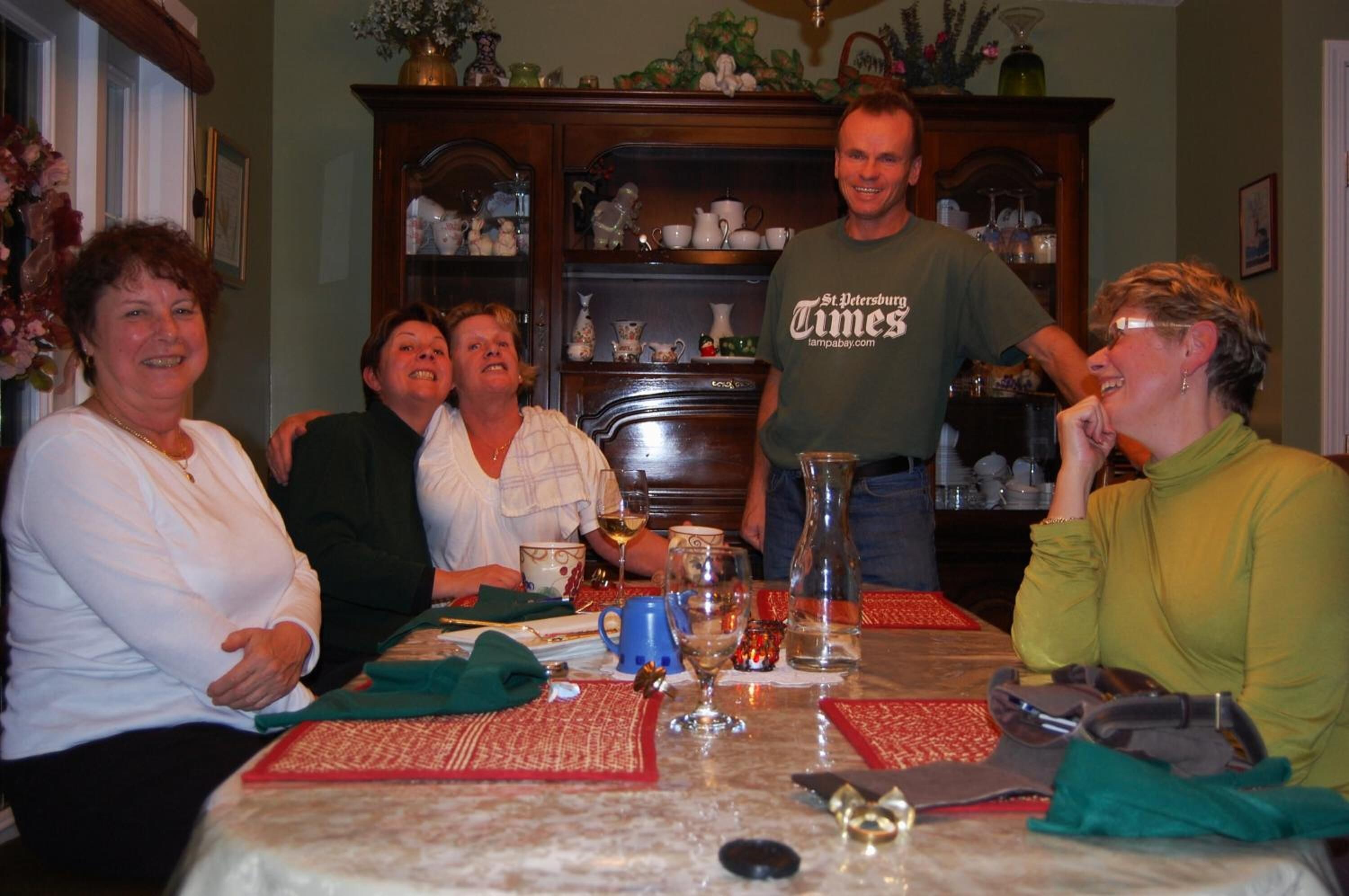 Una mesa de comedor con un florero, copas de vino y una jarrón.