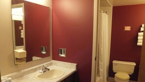 Een badkamer met een marmeren wastafel, toilet en douchegordijn.