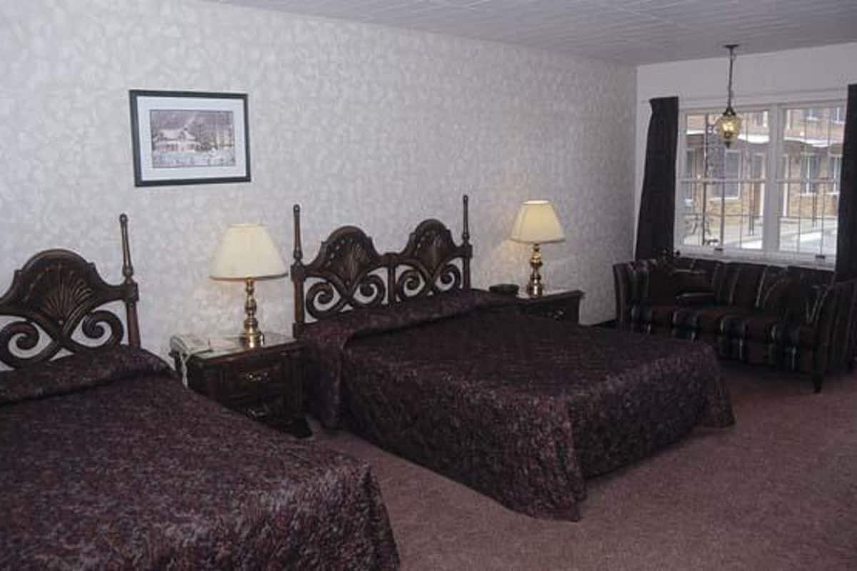 A hotel room with two beds, a sitting area with a sofa, and a window with curtains.