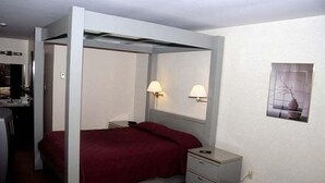 Een eenpersoonskamer met een hemelbed, bedlampjes, een klein tafeltje en een nachtkastje.