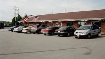 A parking lot with several cars parked in front of a building with a Canadian flag and an American flag.