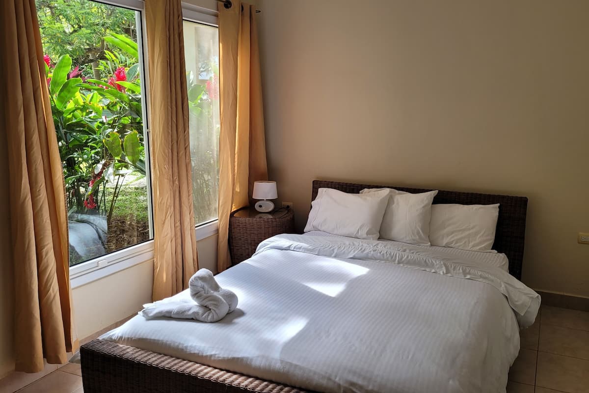 A hotel room with a bed, a nightstand with a lamp, and a window with curtains.