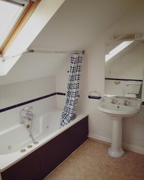 A bathroom with a bathtub, shower curtain, sink, and a skylight. - Bristol Serviced Lettings - Filton (Bristol)
