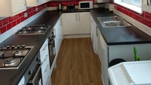 A compact kitchen with white cabinets, a microwave, a gas stove, and a sink. - Bristol Serviced Lettings - Filton (Bristol)