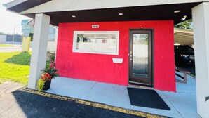 A red and white motel with a sign indicating it is a motel and office, a black door, and a small window. - Bestway Motel (Windsor)