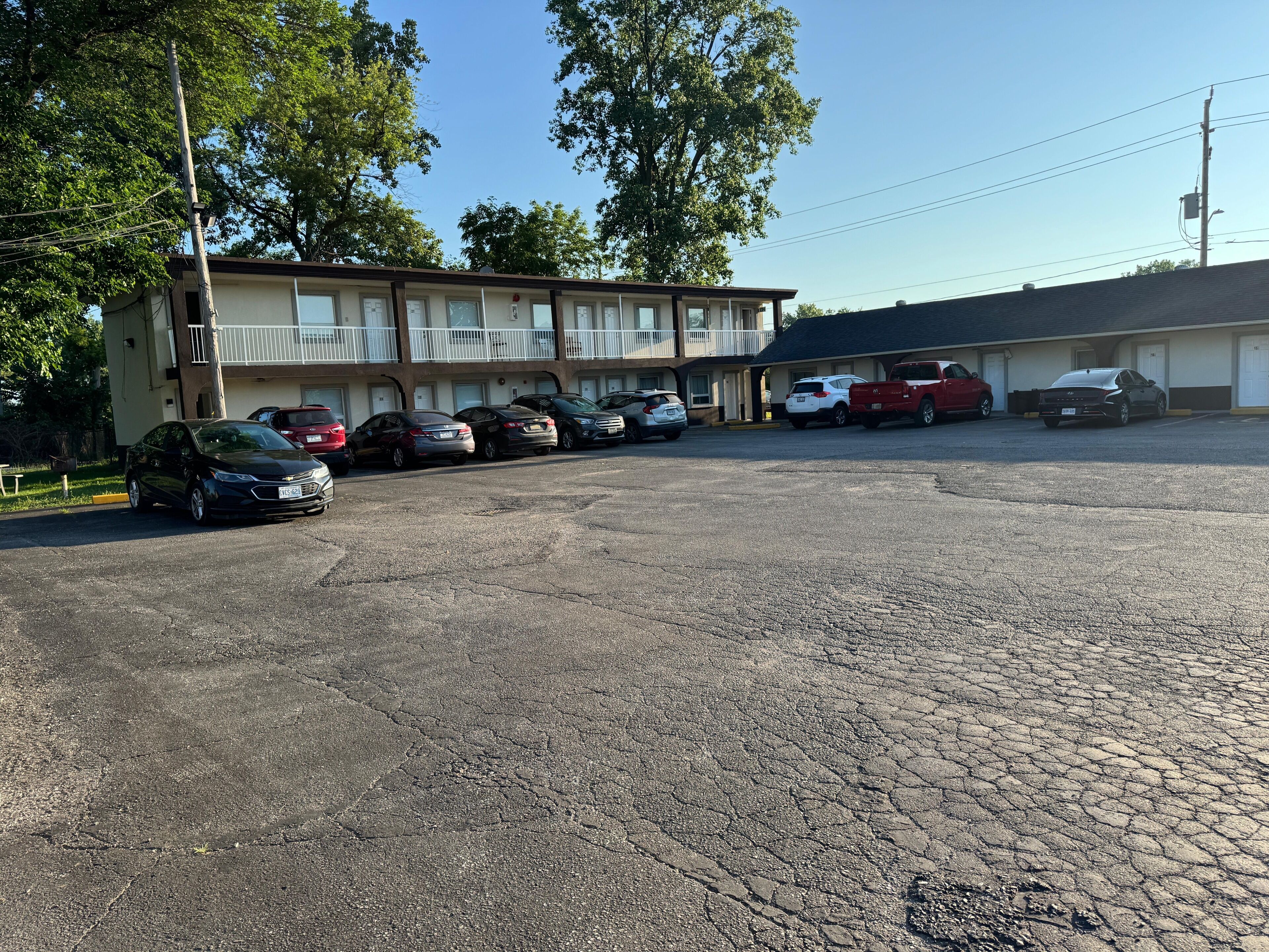 A parking lot with several cars parked in front of a two-story building with a balcony.