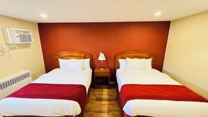 A hotel room with two beds, each with a wooden headboard, white bedding, and red bedspreads. There is a nightstand with a lamp between the beds, and an air conditioning unit mounted on the wall. - Bestway Motel (Windsor)