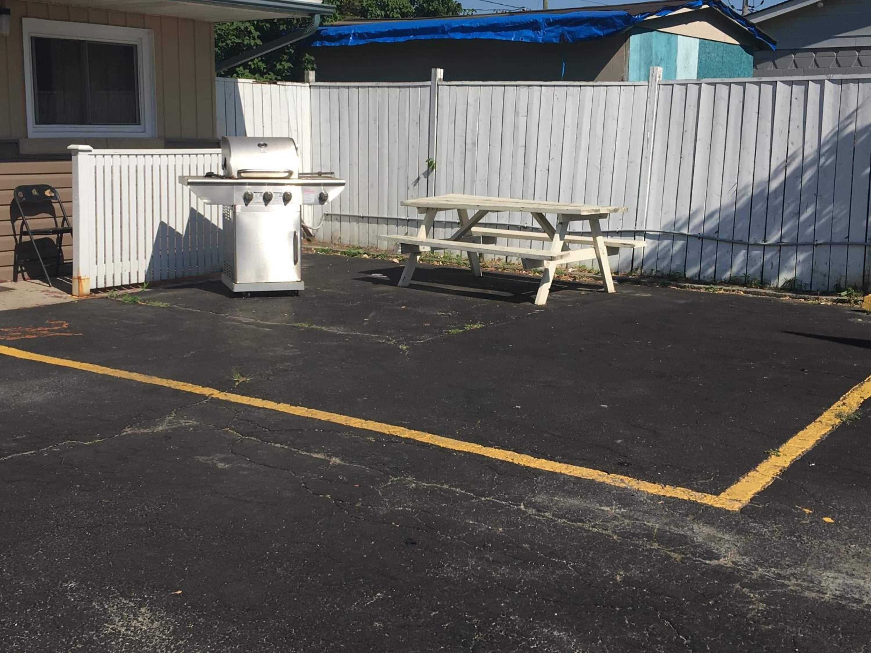 A parking area with a barbecue grill and picnic table.