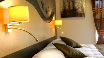 Hotelkamer met een bed, twee kussens, een nachtkastje, een lamp en een schilderij aan de muur.