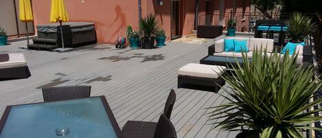 Une terrasse extérieure aménagée avec des meubles en osier, une table de billard et des plantes en pot.
