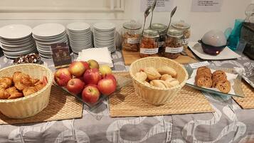 A buffet table with various food items including apples, pastries, and jars of organic spreads.